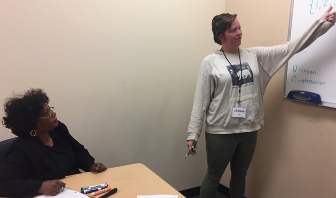 Instructor helping a student with their work, using the whiteboard.