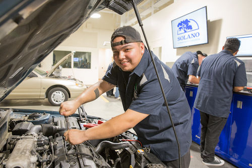 Automotive student working on a car engine.