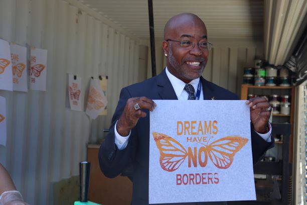 Bryan Stewart holding up a dreams have no borders poster. 
