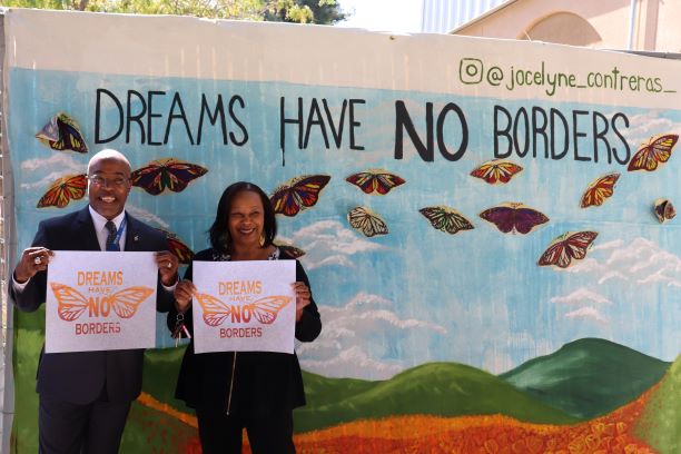 Student service staff members posing in front of the mural.