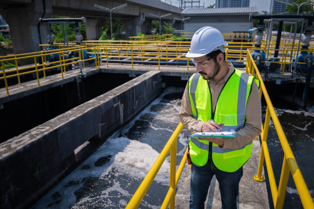 A person in a hardhat and safety vest inspecting a water plant