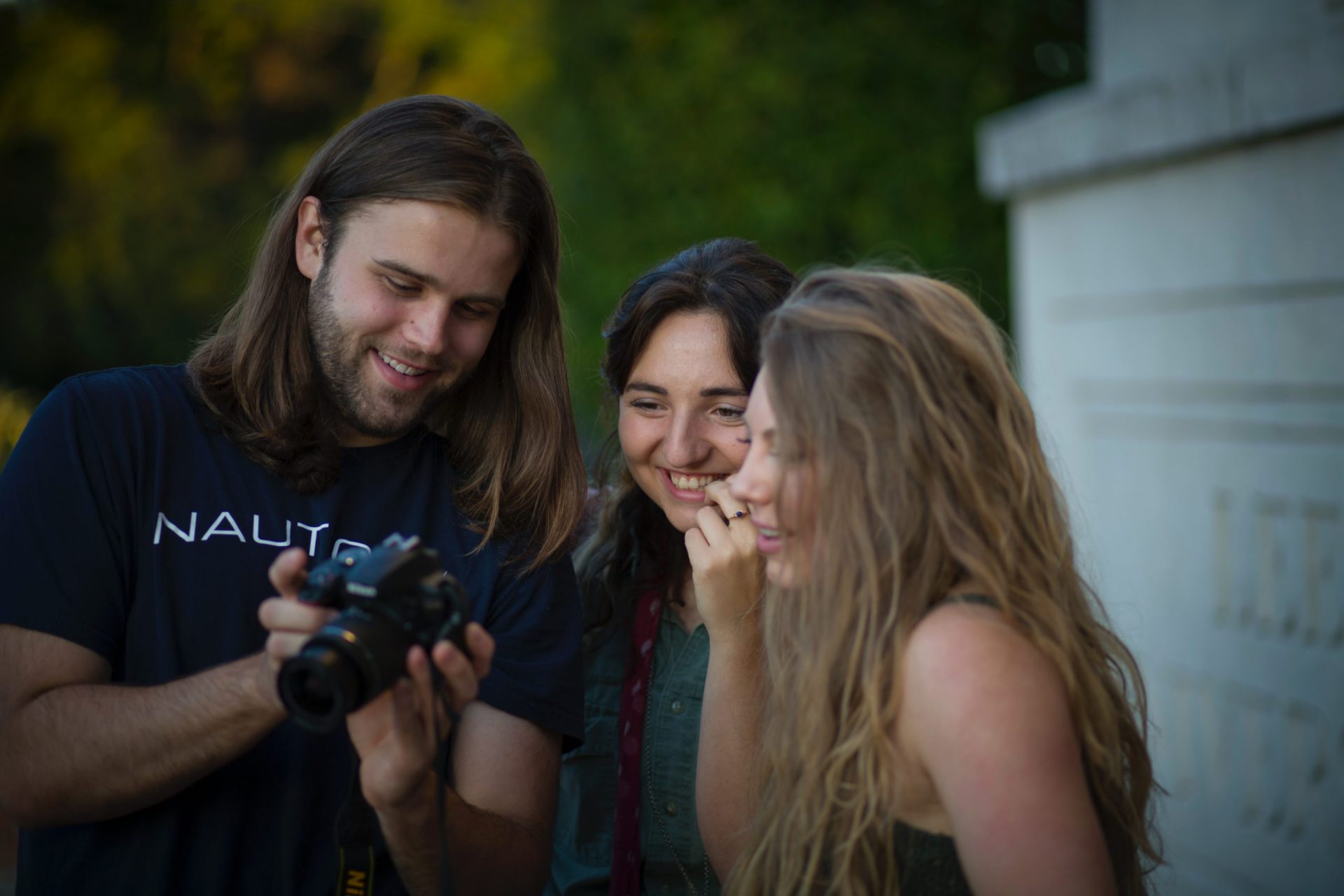 Three people smiling and looking at a photo on a camera