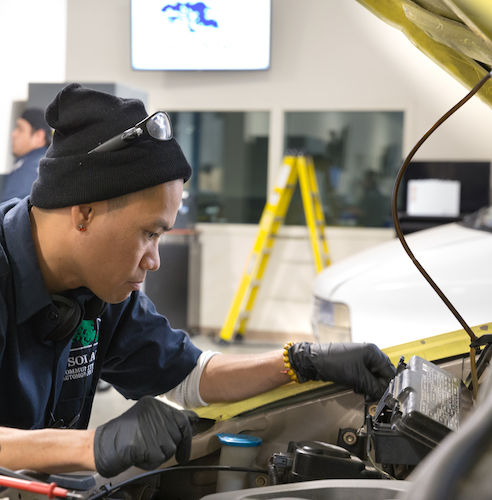 Automotive Technician Student working on a car engine.