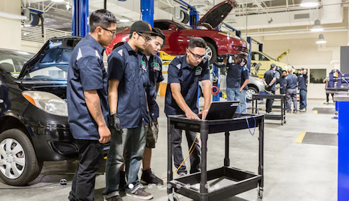 Automotive students working on a car engine