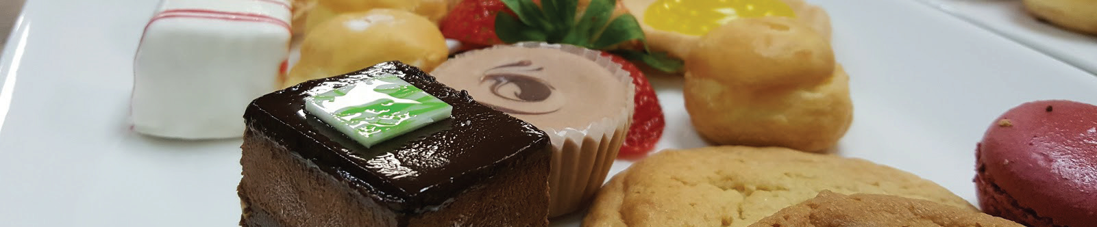 Assorted small desserts on plate. Brownies, cholocolates, strawberries, and macaroons.