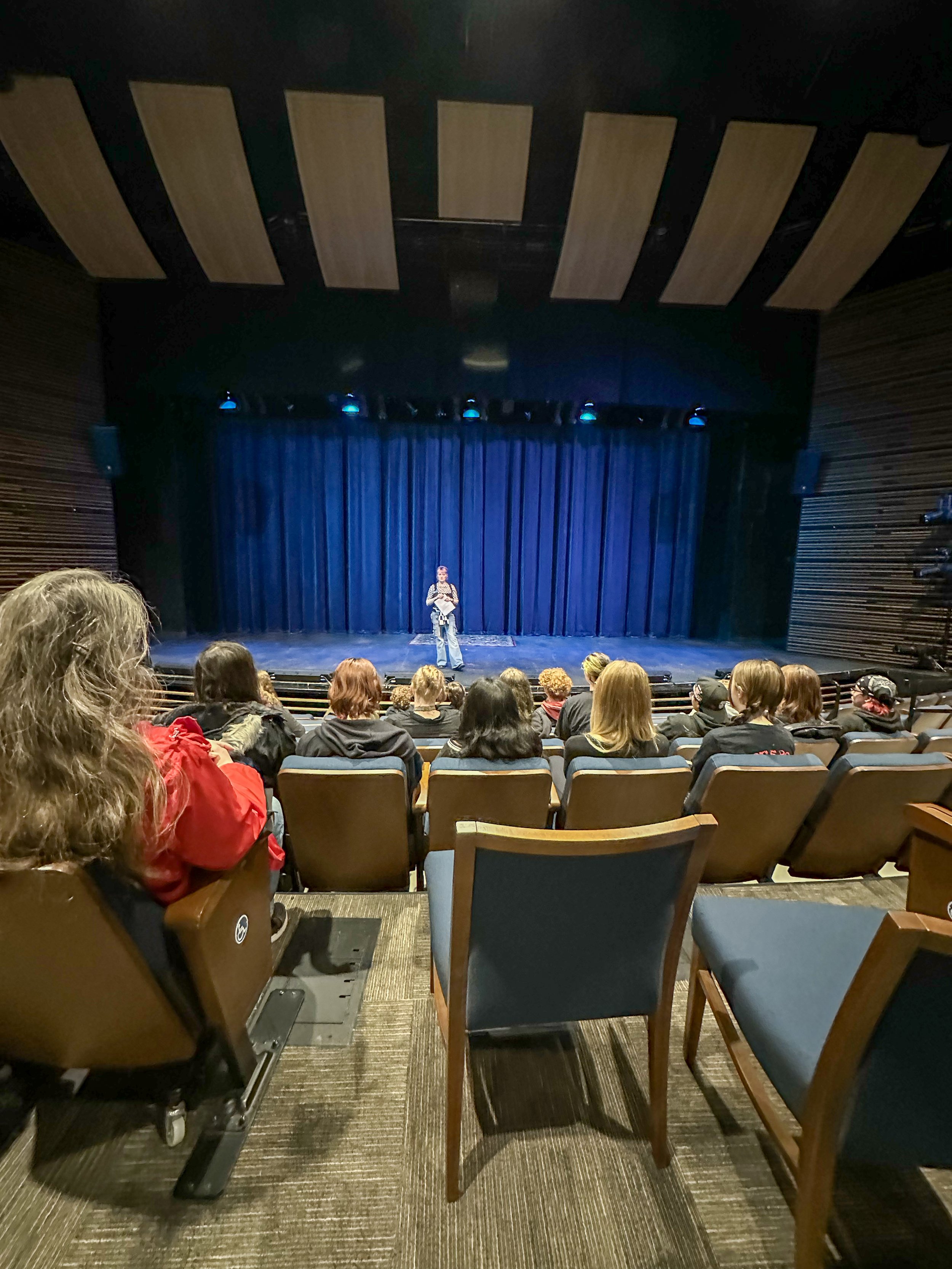 A person on stage with people in audience